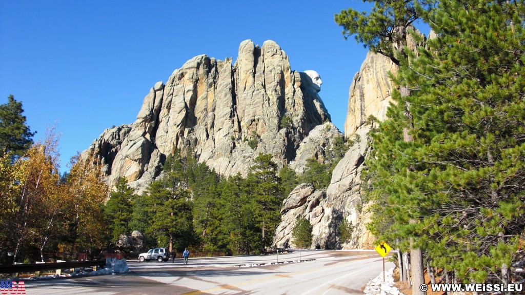 Mount Rushmore National Memorial. - Strasse, Schild, Tafel, Felsen, Bäume, Berg, Mount Rushmore National Memorial, Parkplatz, Abraham Lincoln, George Washington, Theodore Roosevelt, Thomas Jefferson, Denkmal, Black Hills, Mount Rushmore, National Memorial, Bergkette - (Keystone, South Dakota, Vereinigte Staaten)