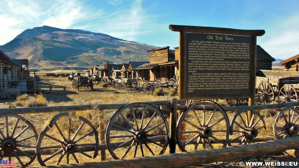 Old Trail Town. Old Trail Town - Museum of the Old West. - Gebäude, Tafel, Zaun, Holzhaus, Holzhütte, Wild West, Old Trail Town, Museum of the Old West, Wilder Westen, Eingangsschild, Räder, Wagenräder - (Cody, Wyoming, Vereinigte Staaten)