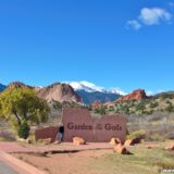 Garden of the Gods. Schild am Haupteingang des Parks. Im Hintergrund sieht man den mit Schnee bedeckten Gipfel des Pikes Peak. - Schild, Sehenswürdigkeit, Tafel, Einfahrtsschild, Sandstein, Sandsteinformationen, Park, Ausflugsziel, Garten der Götter, Naturpark, sehenswert, Kindergarten Rock, Pikes Peak - WEISSINGER Andreas - (Glen Eyrie, Colorado Springs, Colorado, Vereinigte Staaten)